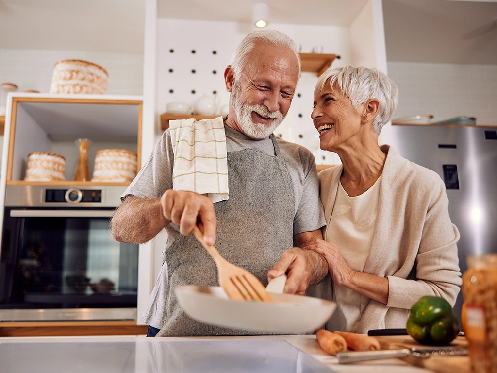older couple cooking a healthy vegan meal with vegetables together