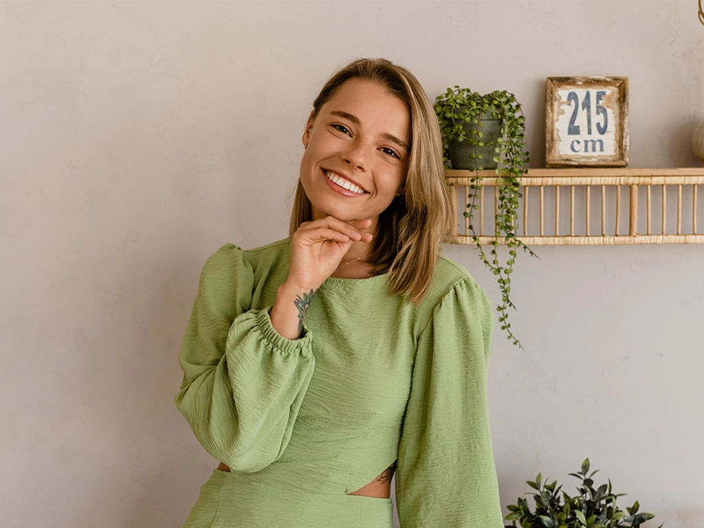 stylish smiling woman in green summer dress in modern interior apartment home